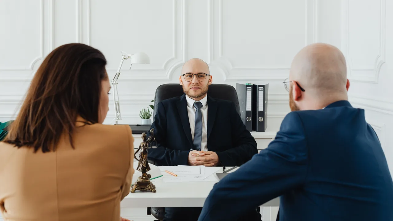 Asesor reunido con dos clientes al otro lado de la mesa