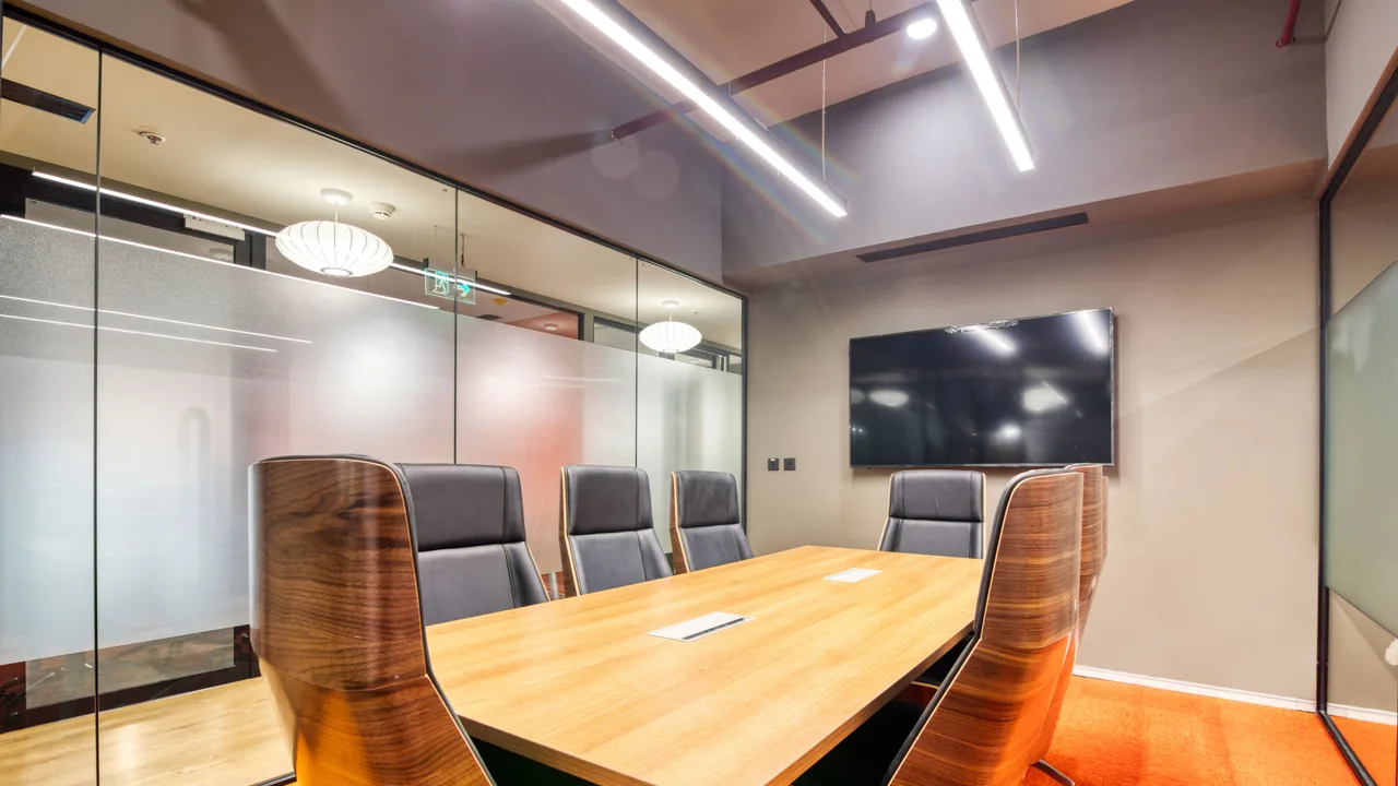 Sala de reuniones vacía con mesa larga y pantalla