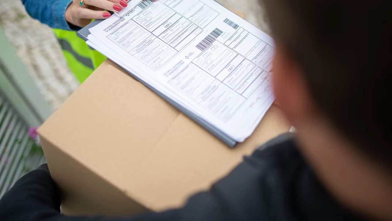 Persona revisando una factura junto a una caja de envío
