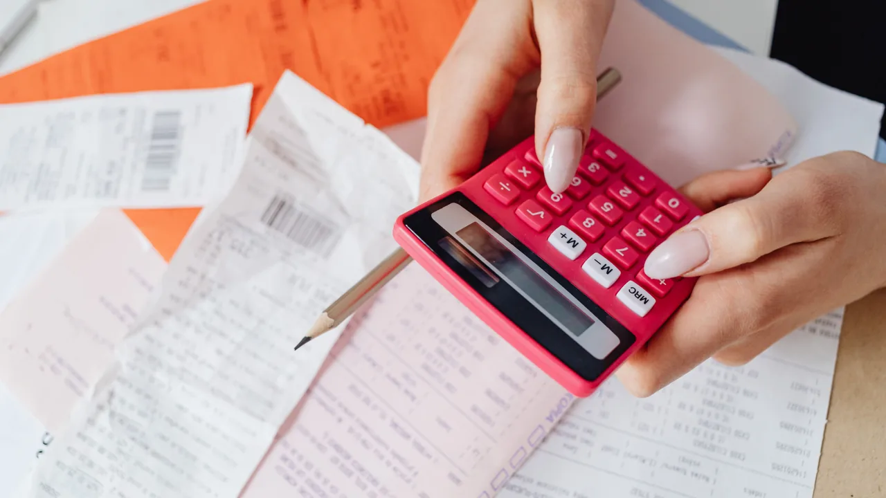 Manos usando una calculadora sobre facturas y hojas de cálculo