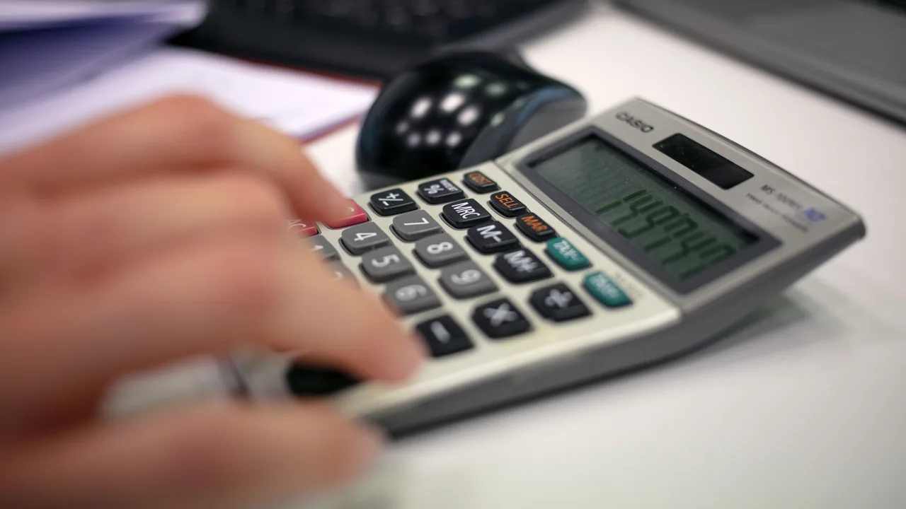 Manos teclando en una calculadora sobre documentos contables